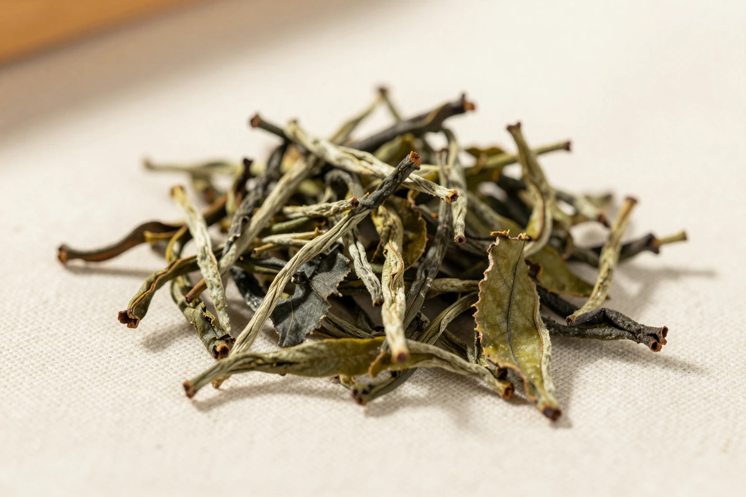 Detail suchých čajových lístků na světlé látce.